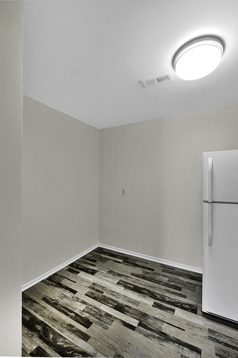 an empty room with a refrigerator in the corner